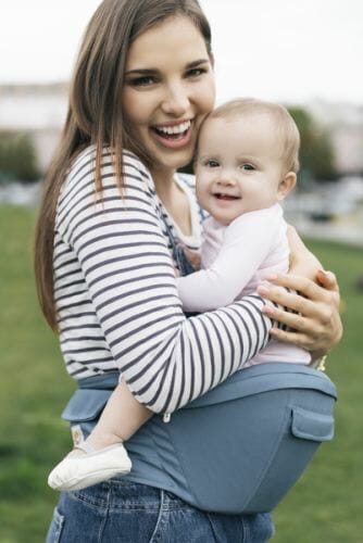 woman holding baby in Ergobaby hip seat carrier