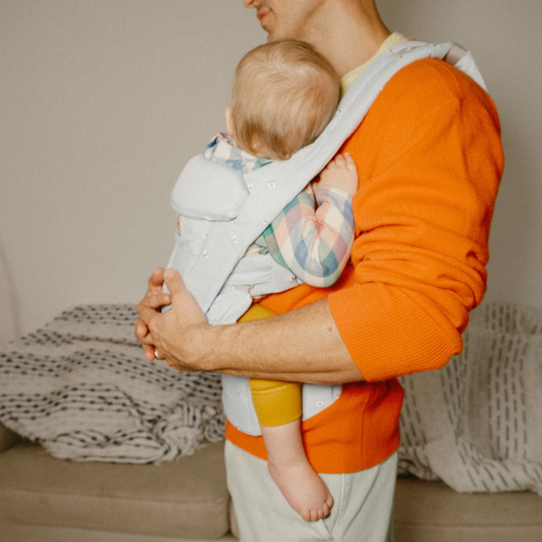Man holding a baby in a light blue baby carrier
