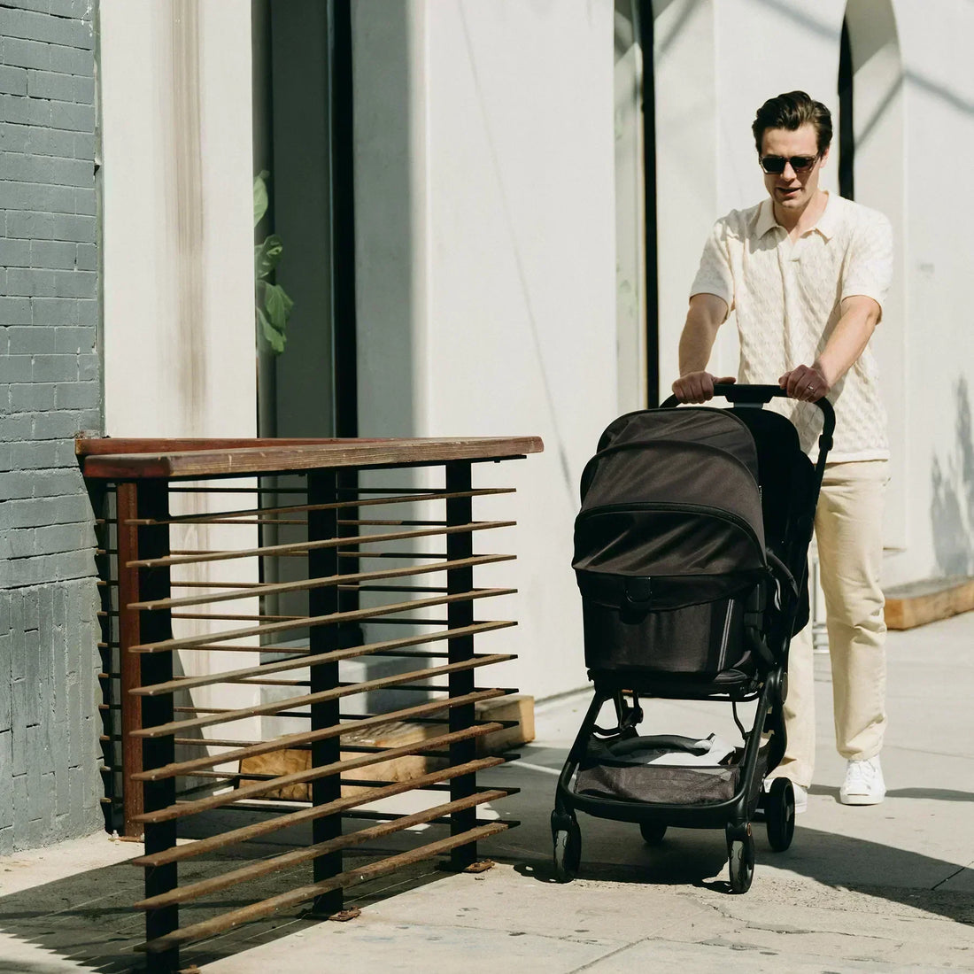 Man pushing black baby stroller outdoors