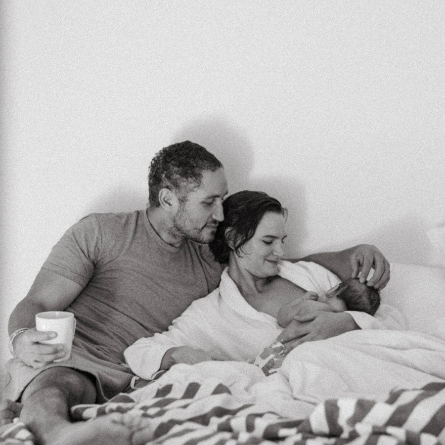 Man and woman in bed while woman breastfeeds