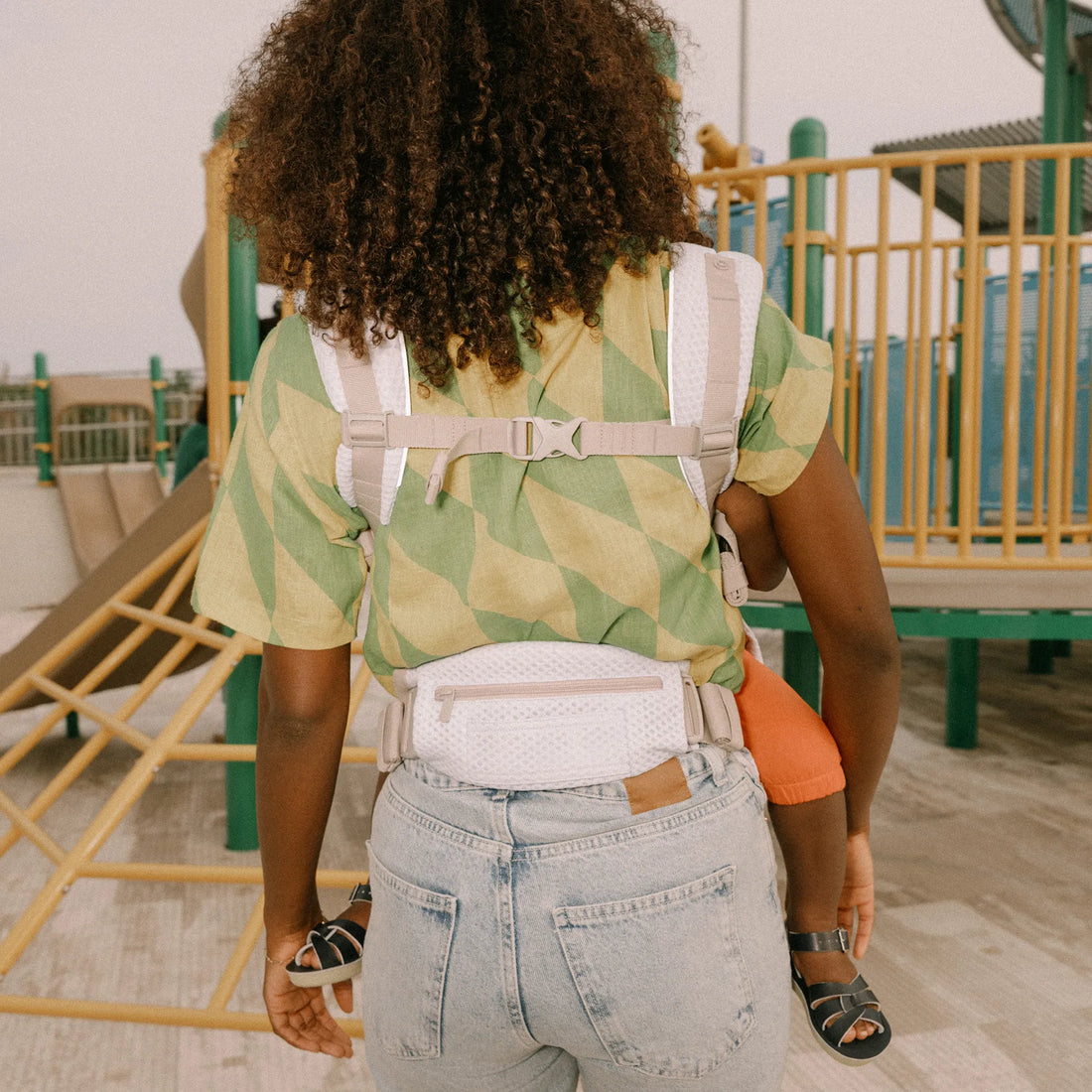 Back of a person holding a baby in a baby carrier
