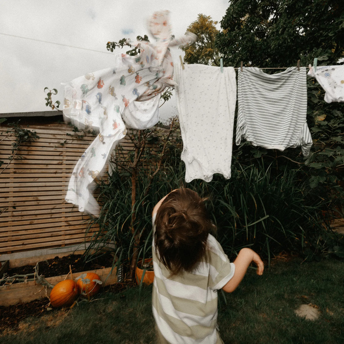 Child looking at clothes hanging on a line outdoors