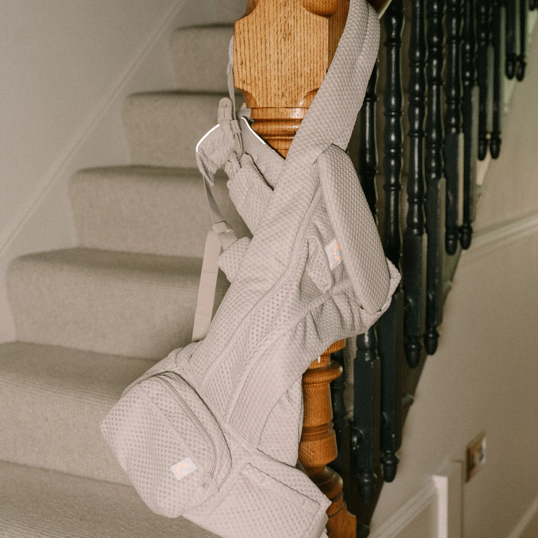 Light grey baby carrier hanging on a pole