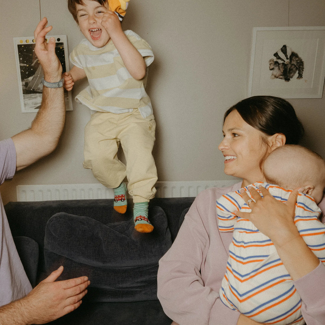 Woman holding a baby while two toddlers play next to her
