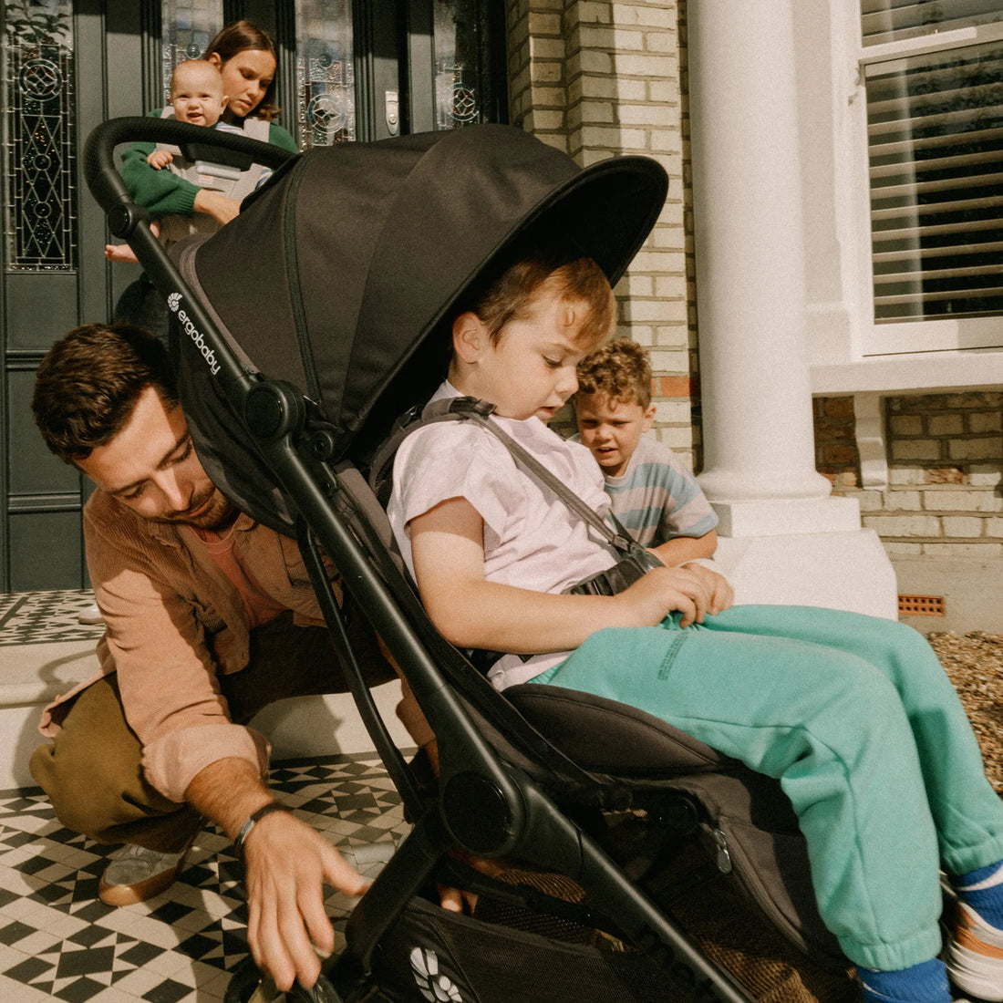 Man pushing toddler in a stroller with family members looking on
