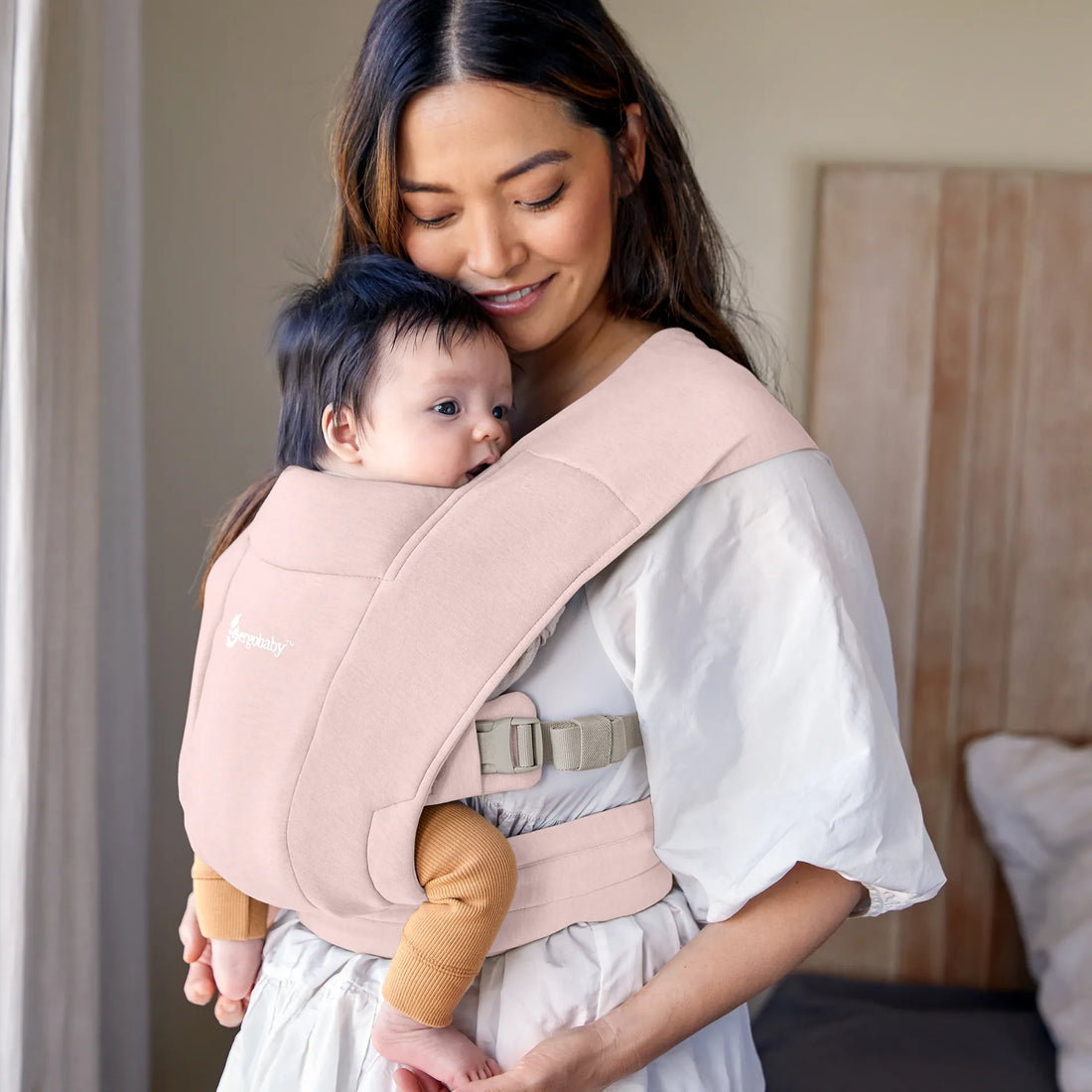 Woman holding baby in pink baby carrier