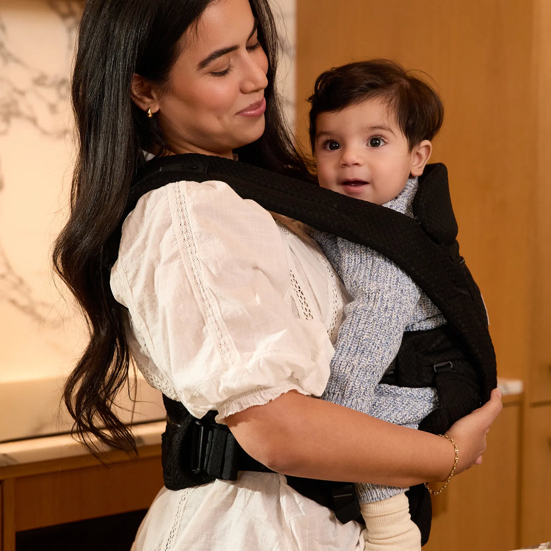 Woman holding baby in a black baby carrier