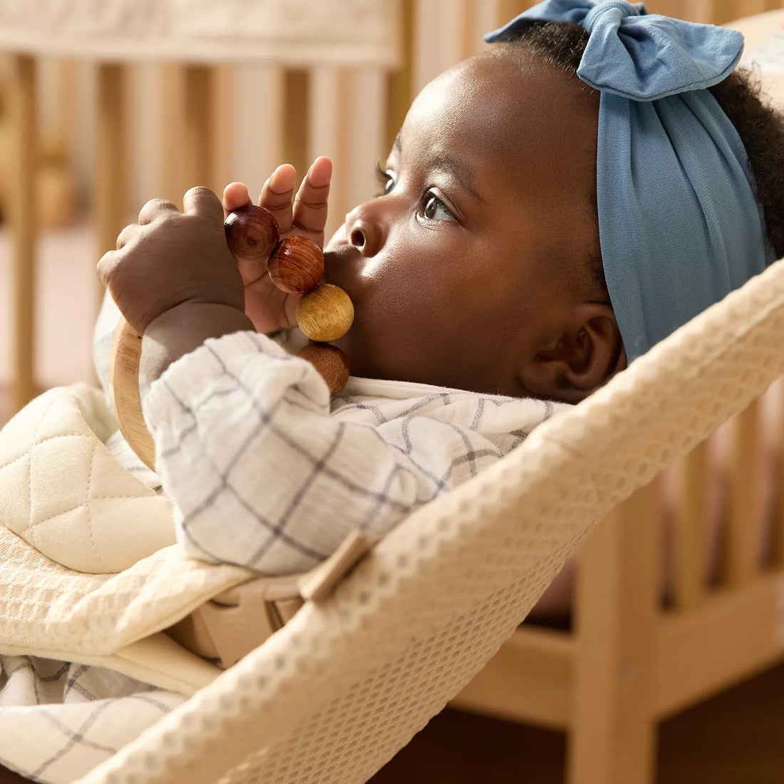 Baby in a blue headband in a baby bouncer
