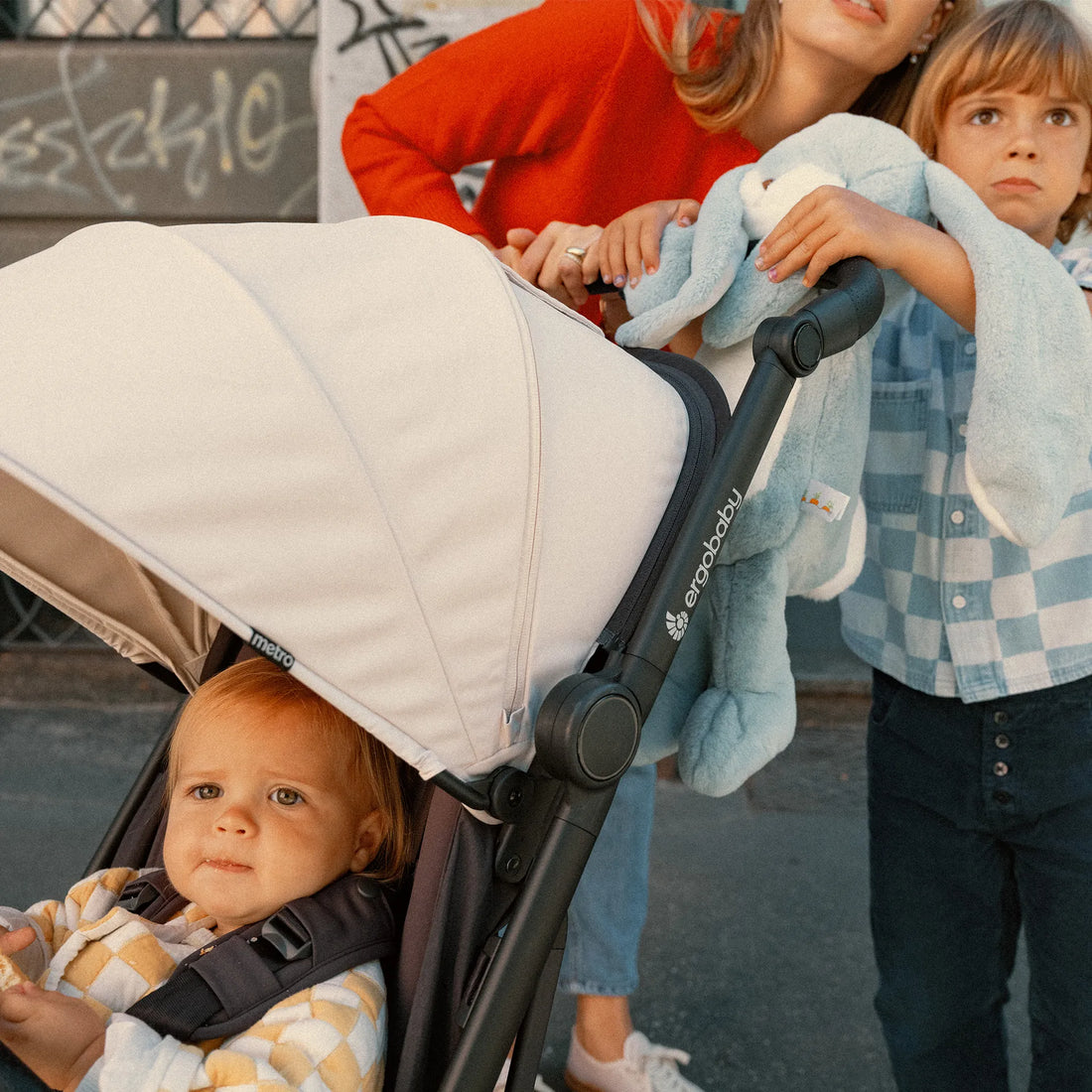 Two kids pushing a baby in a stroller