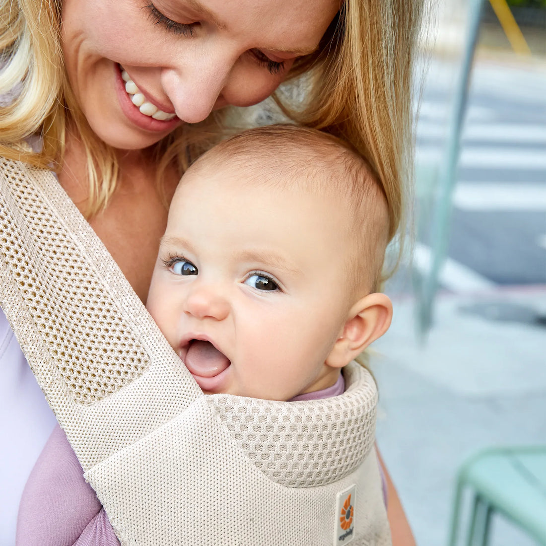 Woman holding a baby in a beige baby carrier