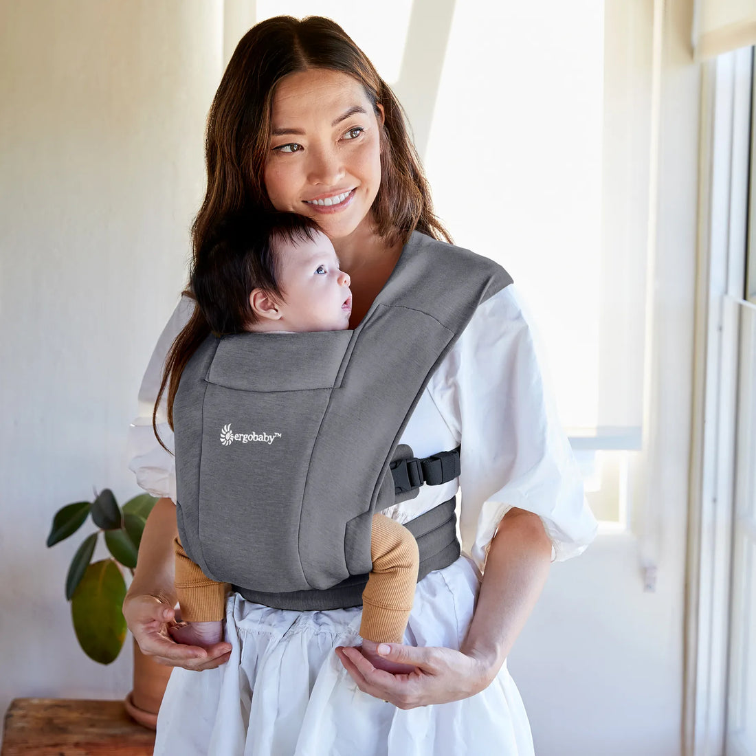 Woman holding a baby in a dark grey baby carrier