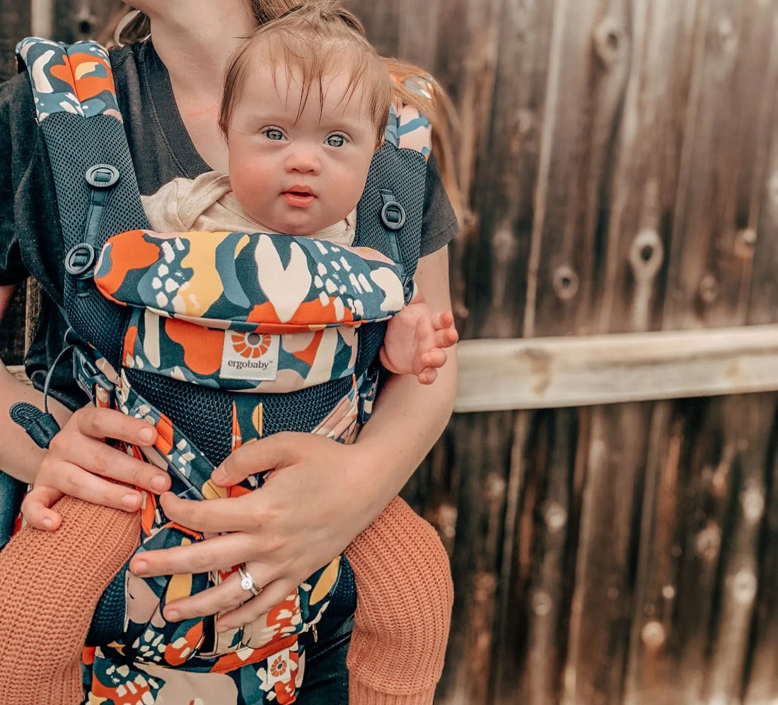 Woman holding a baby in a patterned baby carrier