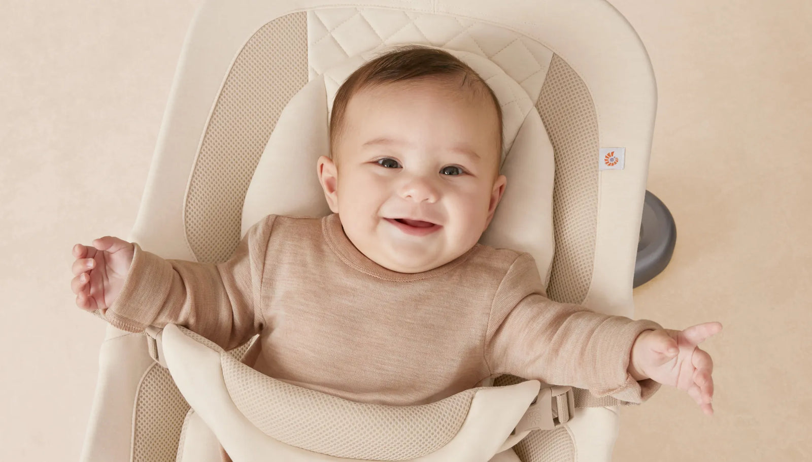 Baby in a beige high chair with a smiling expression