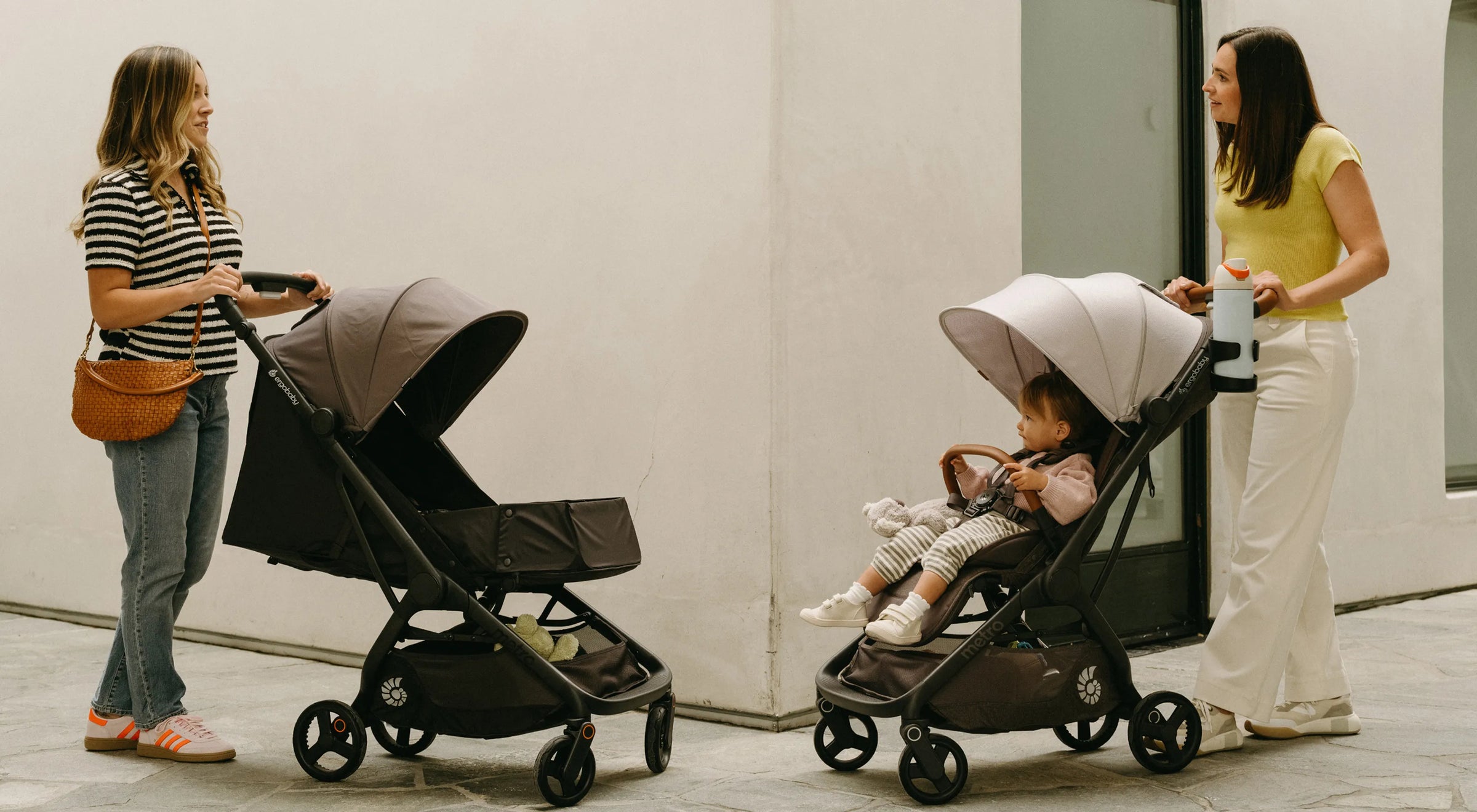 Two women with the Metro 3 and Metro 3 deluxe strollers in a meeting on the corner.