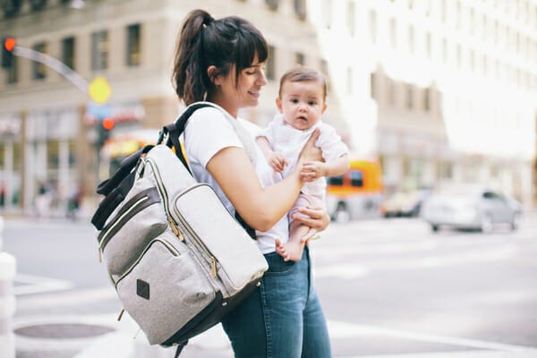 A woman outside with her baby and her Ergobaby Diaper Bag