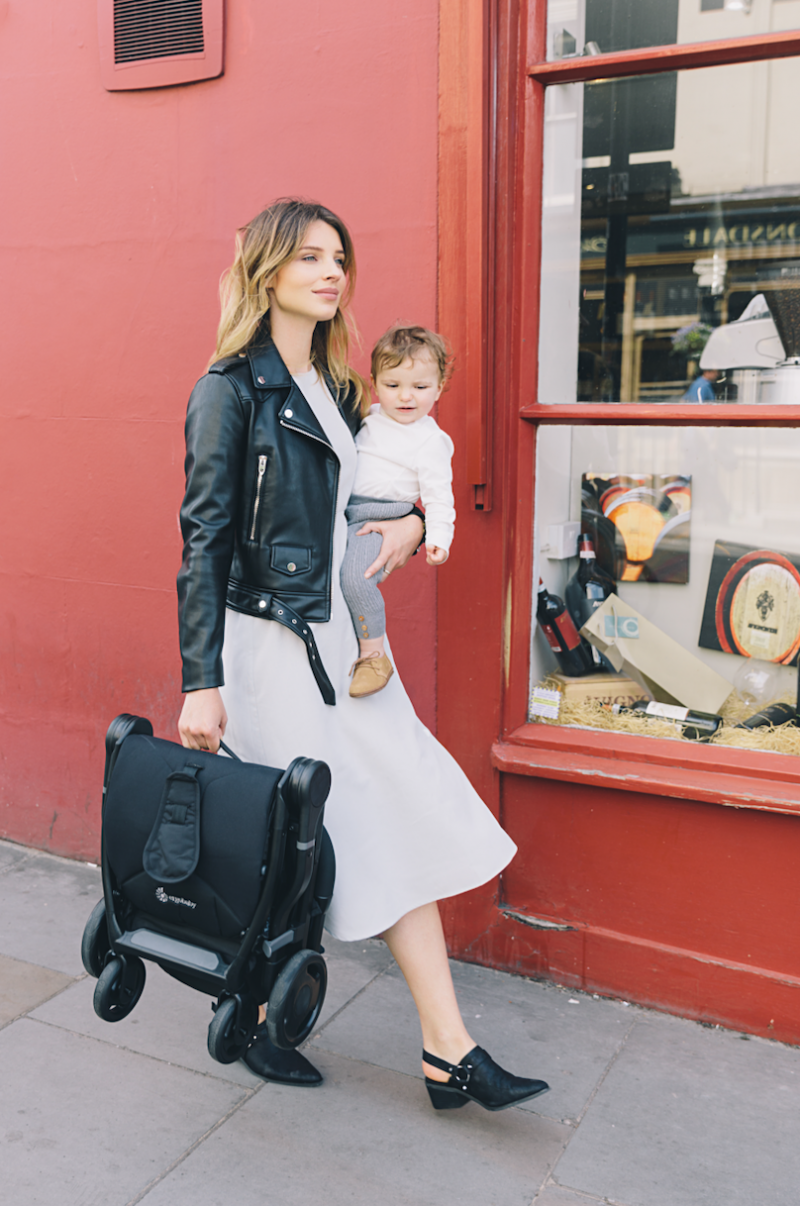 Woman holding baby and compact and lightweight stroller