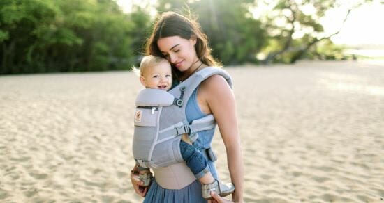 woman carrying baby on beach in Ergobaby carrier