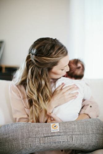 woman using Ergobaby Nursing pillow with baby