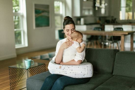 mom holding baby with Ergobaby nursing pillow in lap