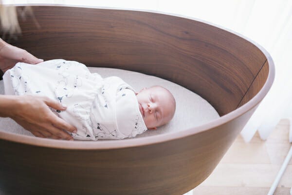 baby in crib in Ergobaby sheep swaddler