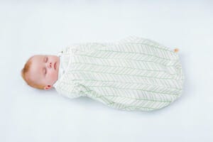 baby sleeping in crib in Ergobaby bamboo swaddler