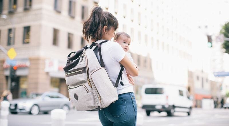 mom holding baby with diaper bag on her back