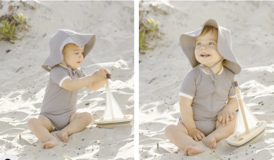 Baby with sun hat playing in the sand