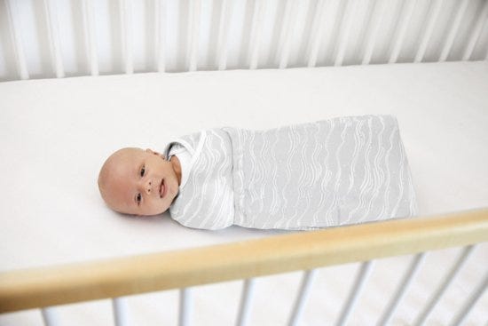 Baby wrapped in a swaddle lying in a crib