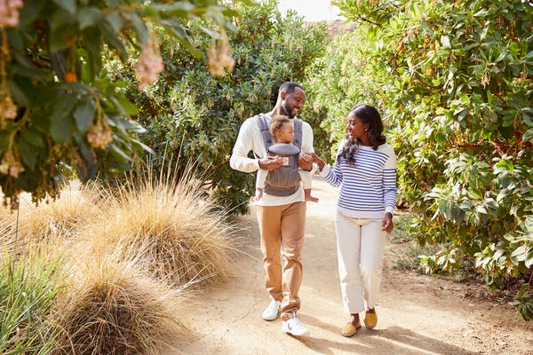 two parents walking with their baby in a baby carrier